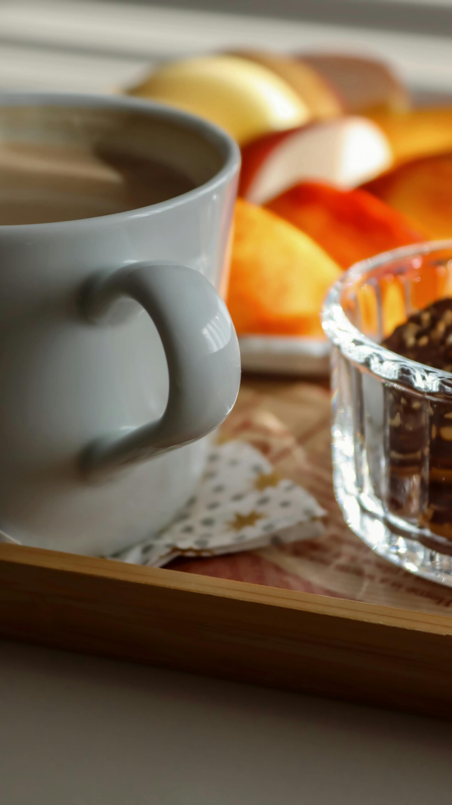 GÎTE ET CHAMBRE Warm morning setup with coffee, sliced fruit, and treats on a wooden tray.